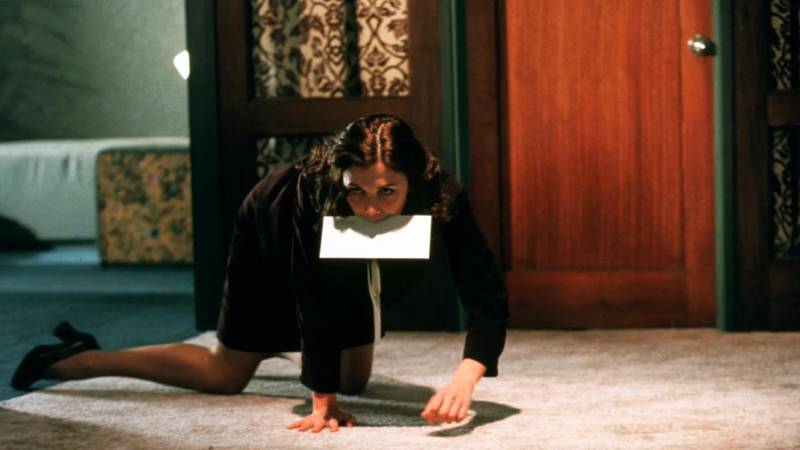 Person crawls on all fours with an envelope in mouth in an office