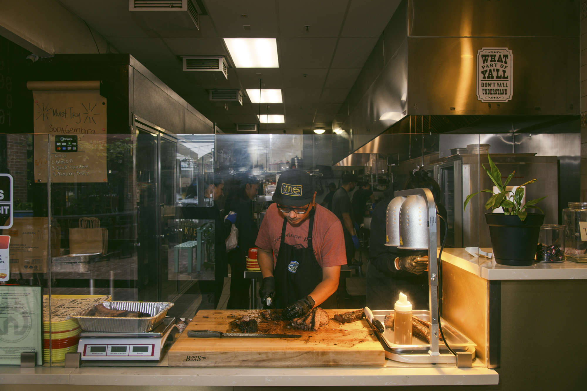 A barbecue pitmaster slices brisket on a wooden chopping block.