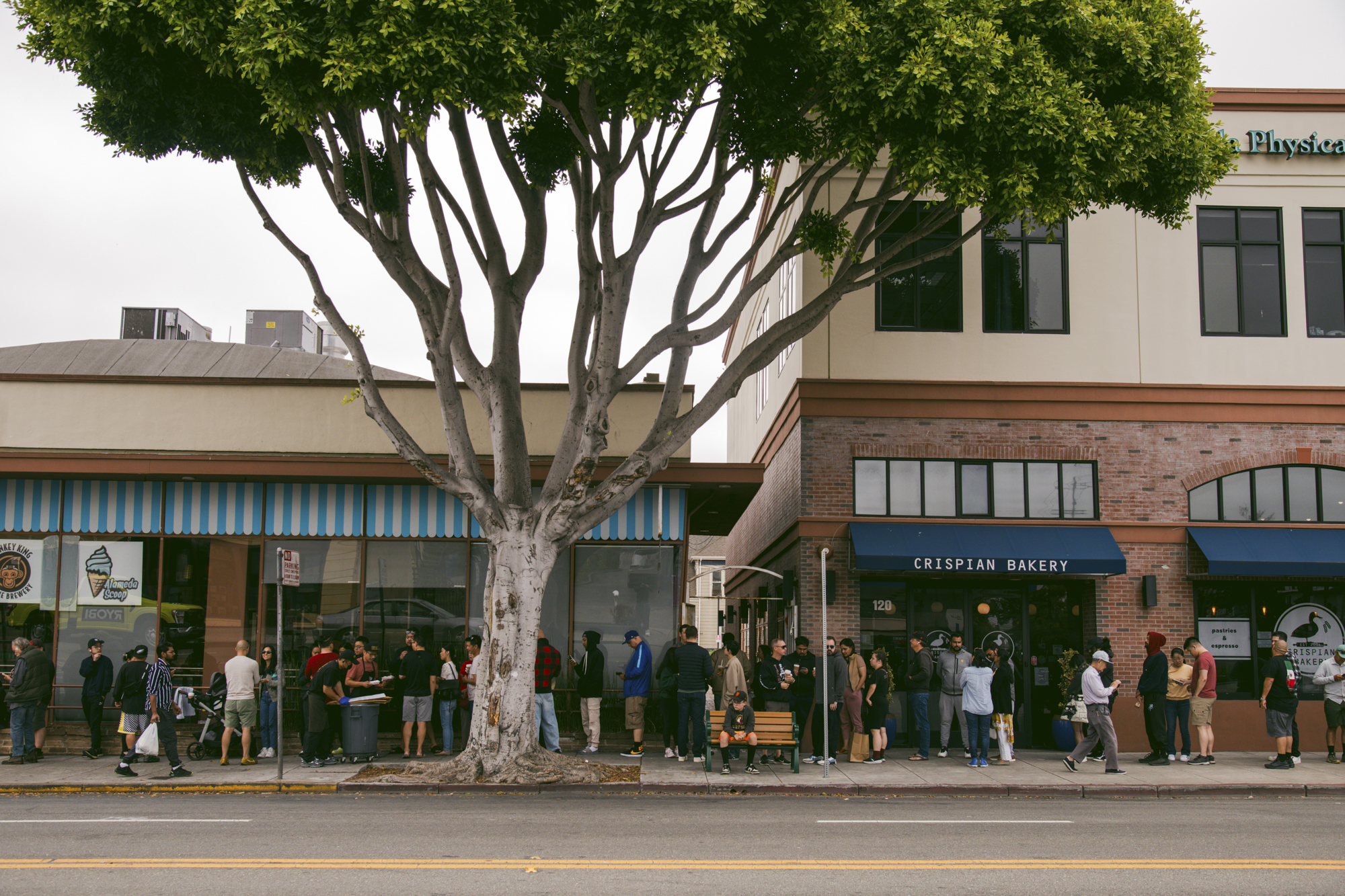 A long line of people on a sidewalk waiting to get into a restaurant