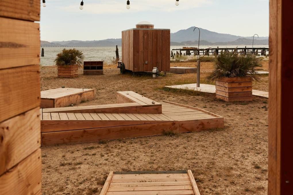 wooden huts, platforms and ramps on shore of bay with mountain across water