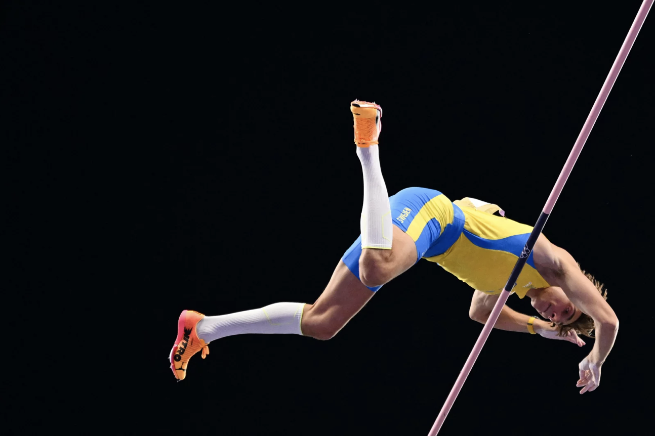 A high-jumper glides over the top of a high jump pole.