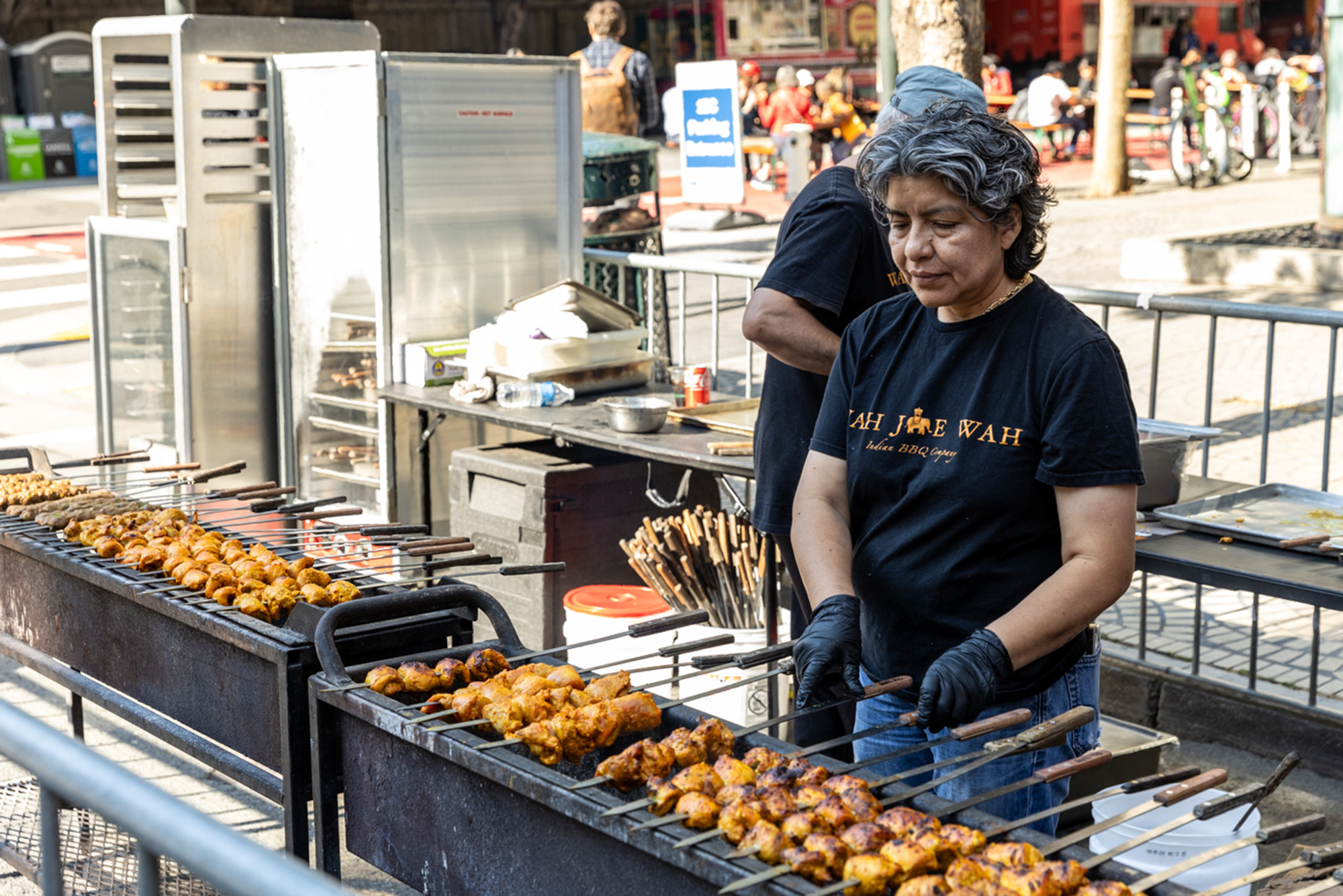 A woman grilling meat skewers over a charcoal grill.