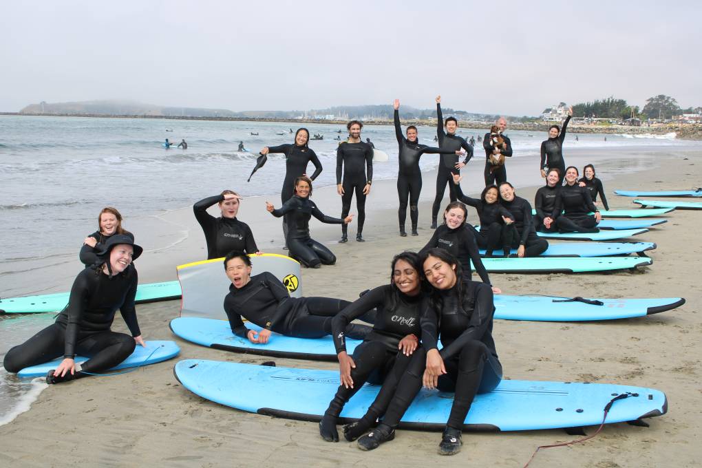 Smiling and hugging surfers pose on the beach pose with their boards.