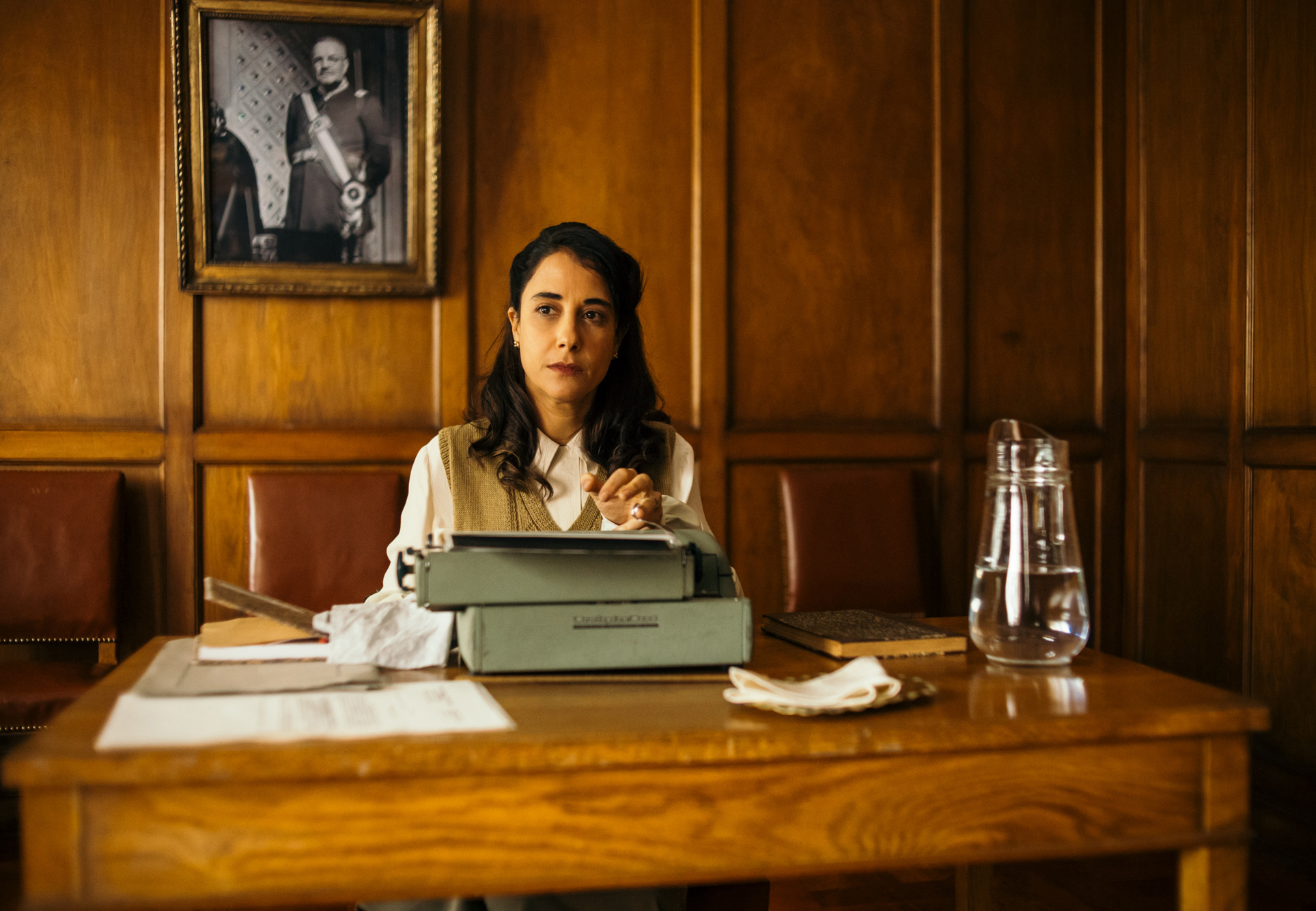 Woman sits behind typewriter at desk