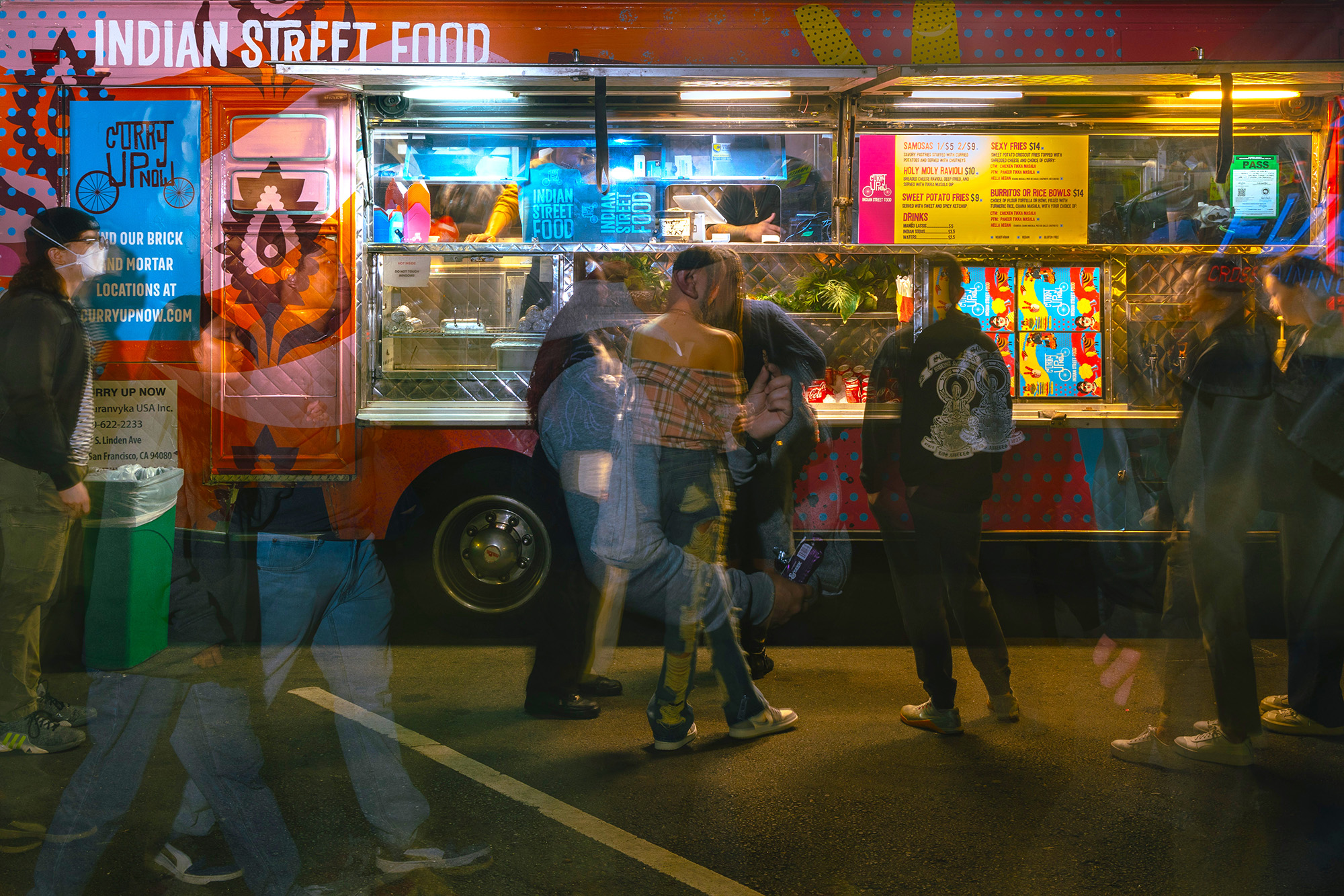 People line up outside a food truck at nighttime.