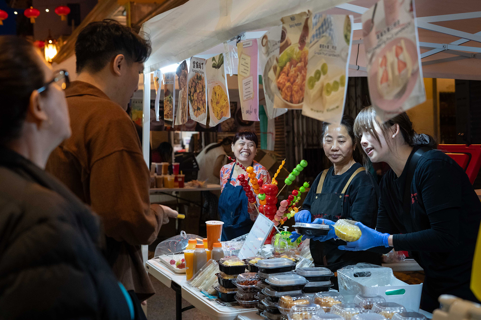 A street vendor sells colorful skewers of candied fruit.