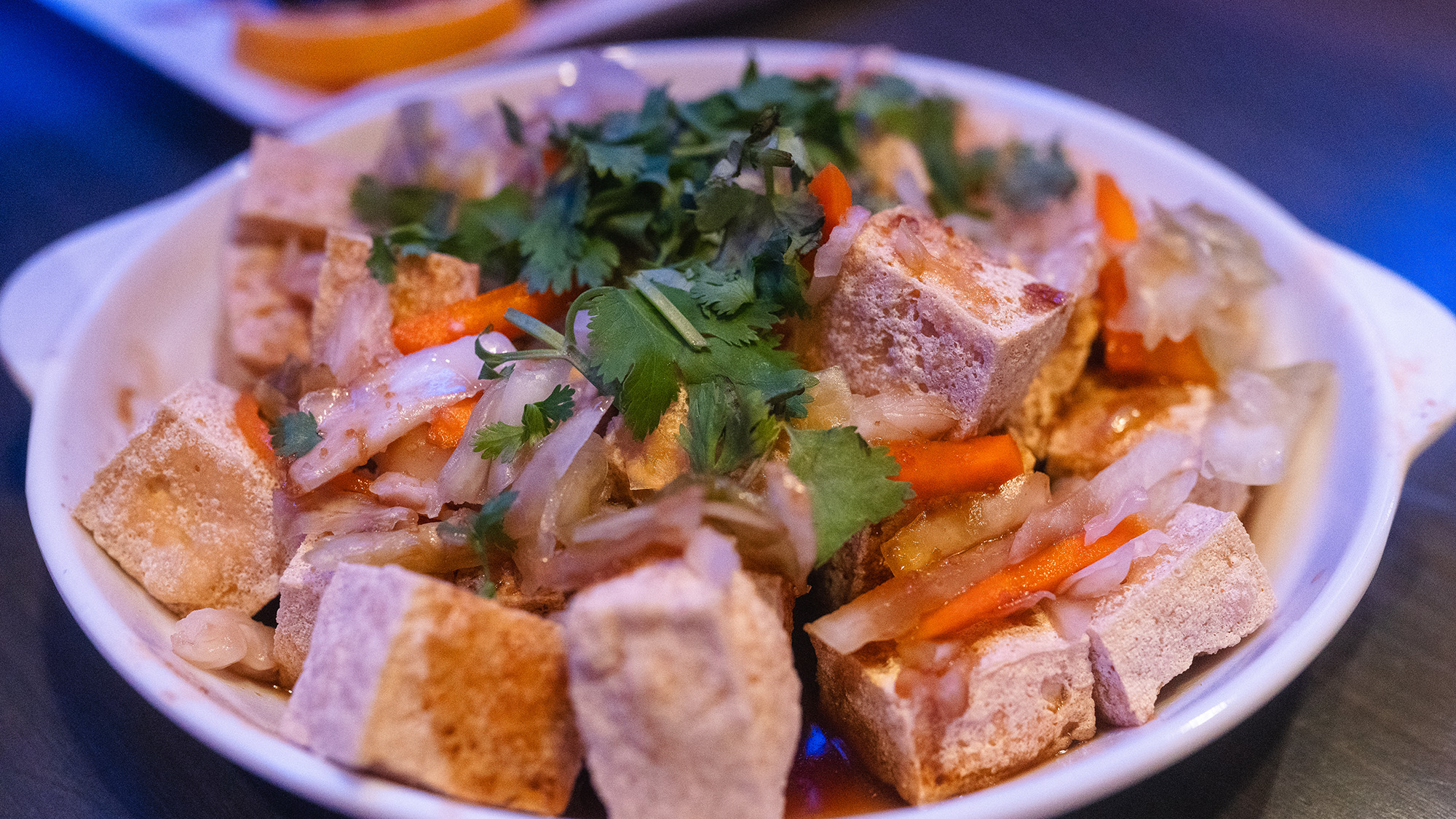 Plate of fried stinky tofu garnished with cilantro and pickled carrots.