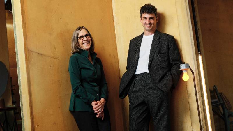 Woman and man smile and lean against walls in a corner