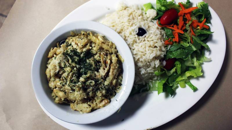 A bowl of Portuguese salt cod with bechamel, served alongside a mount of rice and salad.