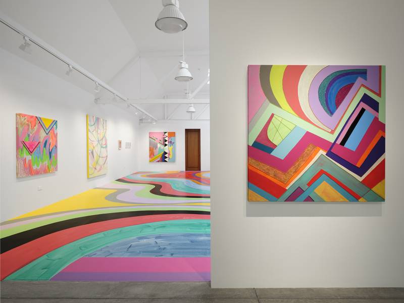 view of gallery with colorful abstract paintings and painted floor