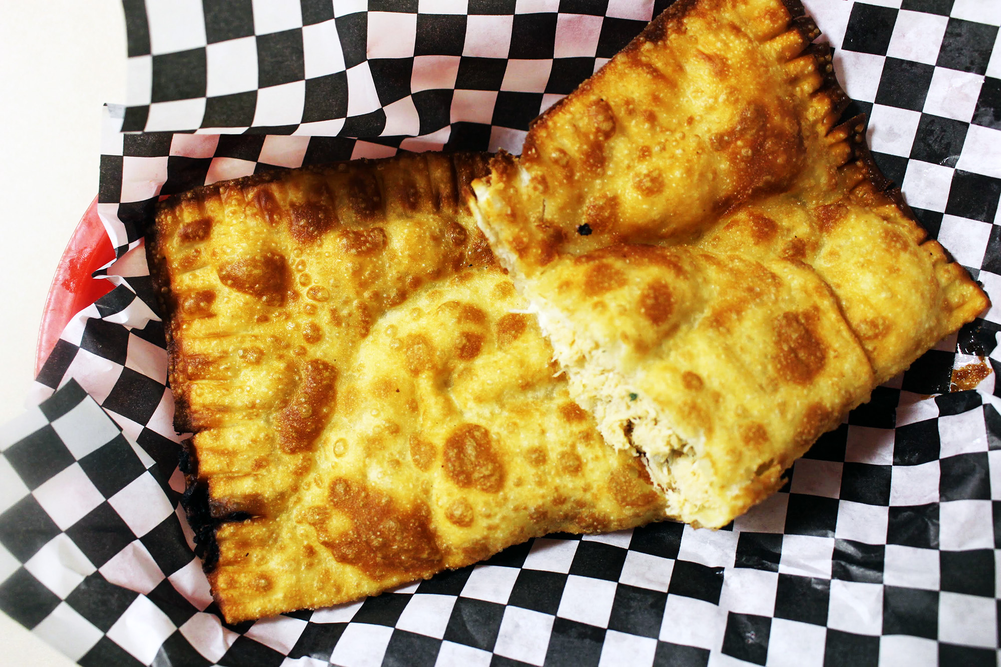 Cheesy fried pastry on checkered paper.