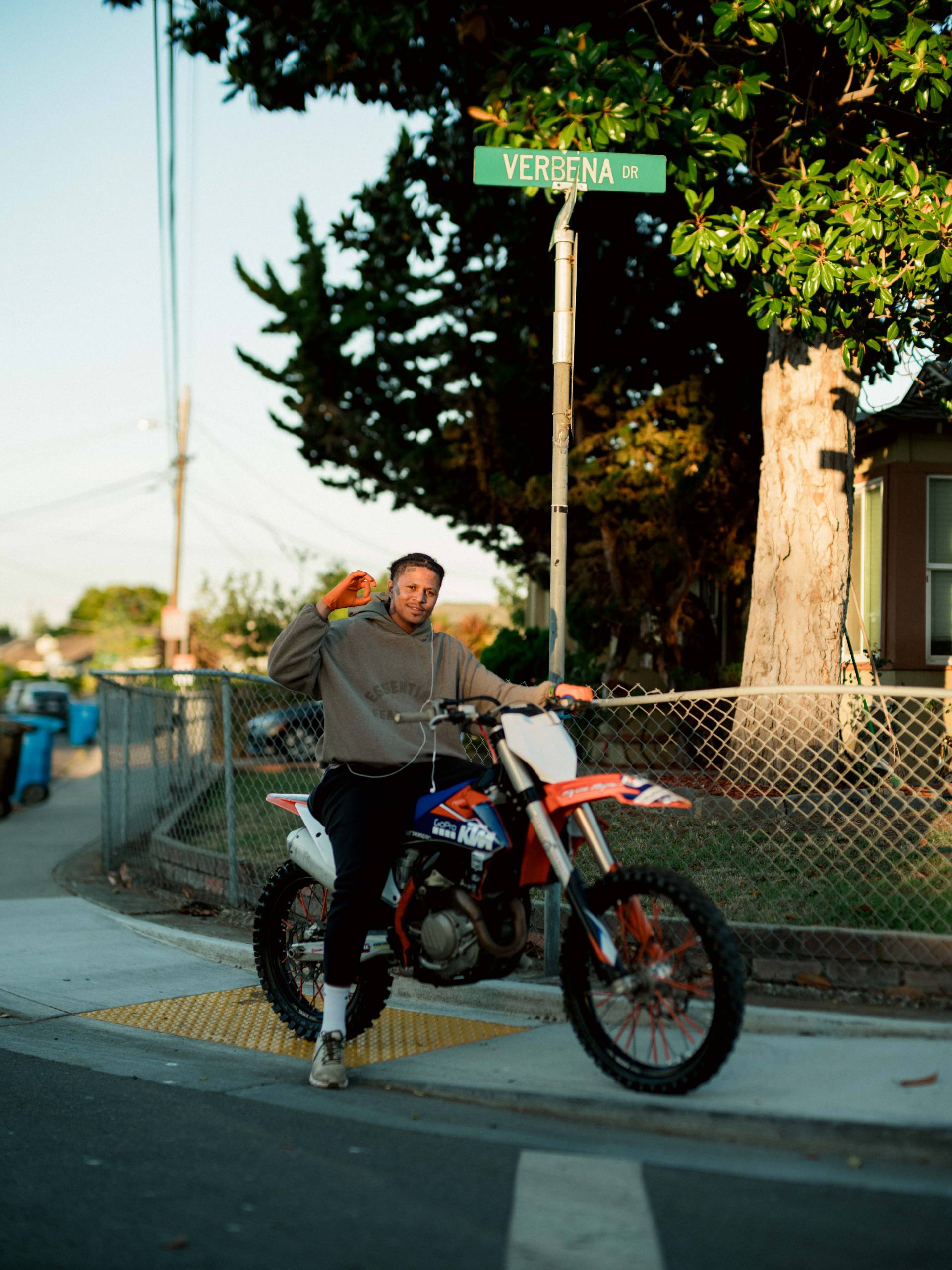 a young man on a motor bike poses on the sidewalk