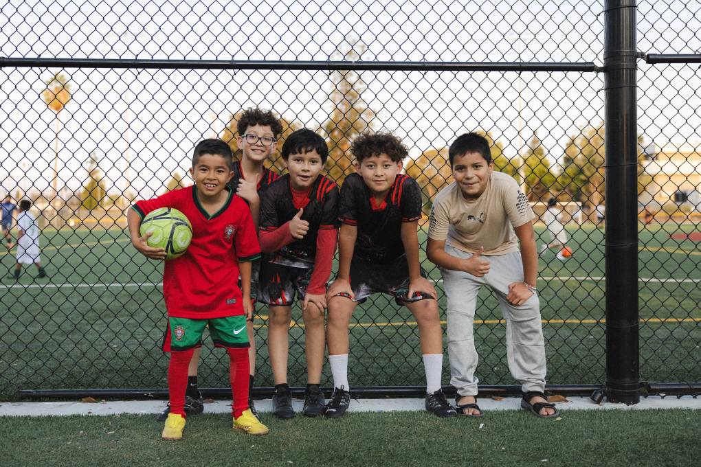 a group of young boys pose for a photo near a soccer field in Sunnyvale