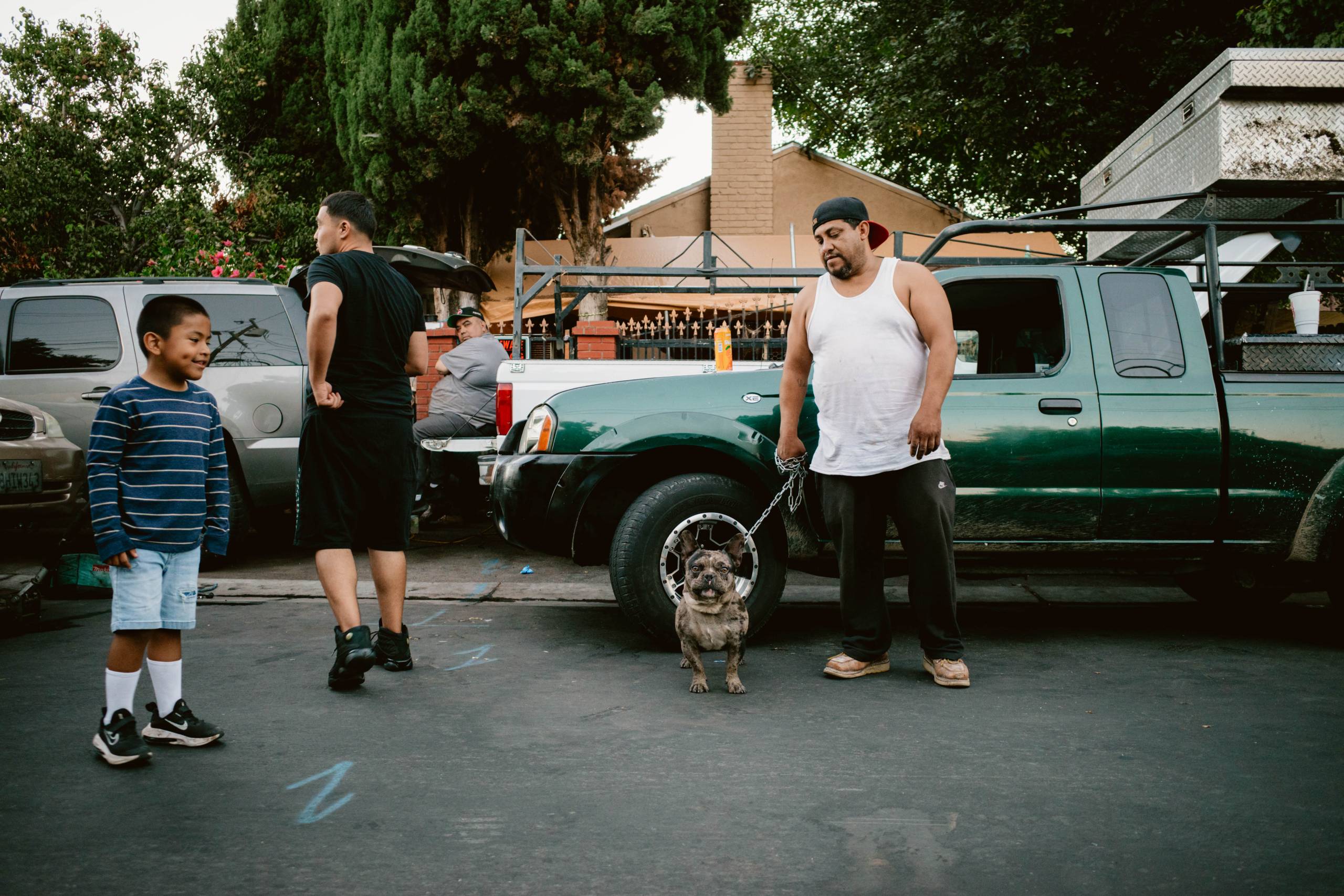 a Latino family stands outside of their home with a dog in East Palo Alto