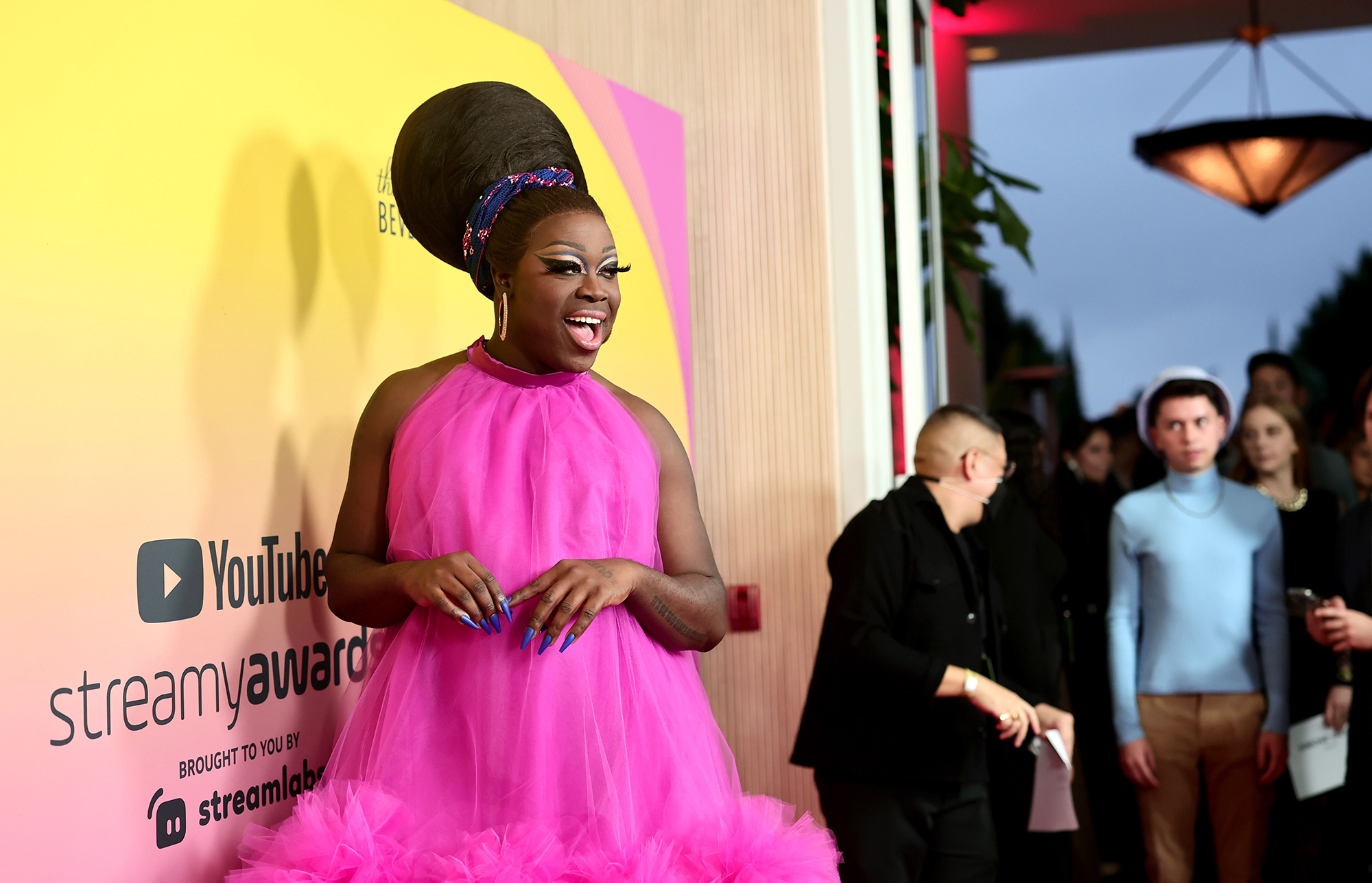 Bob the Drag Queen poses on the read carpet in a hot pink puffy dress and '60s-style updo. 