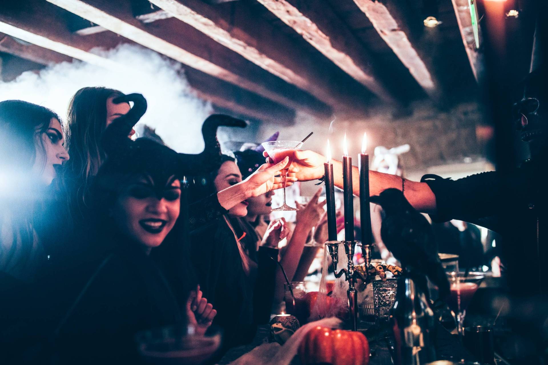 Barman giving cocktail to woman at a busy Halloween party.