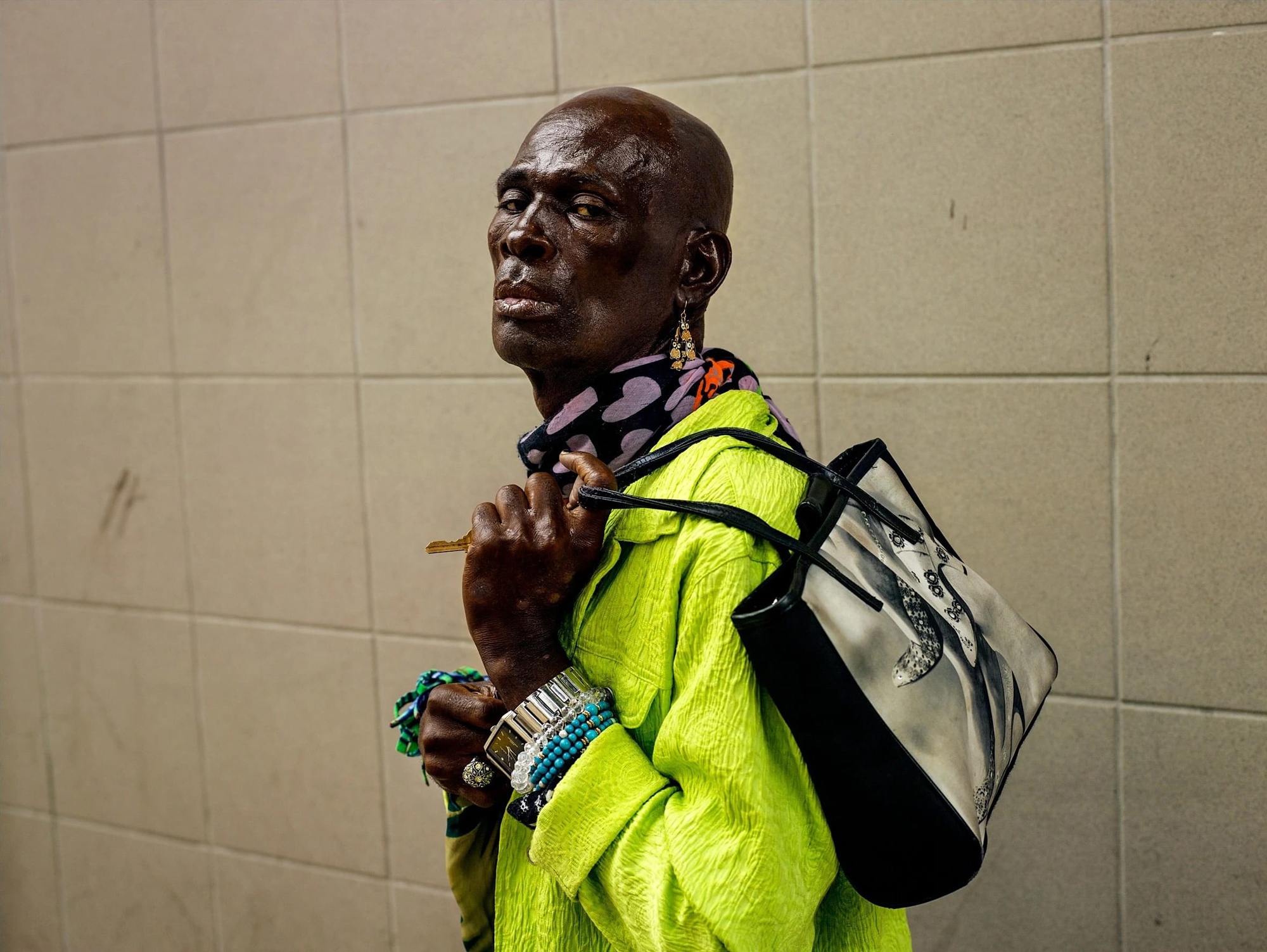 Black man looks over shoulder while holding bag in lime green jacket