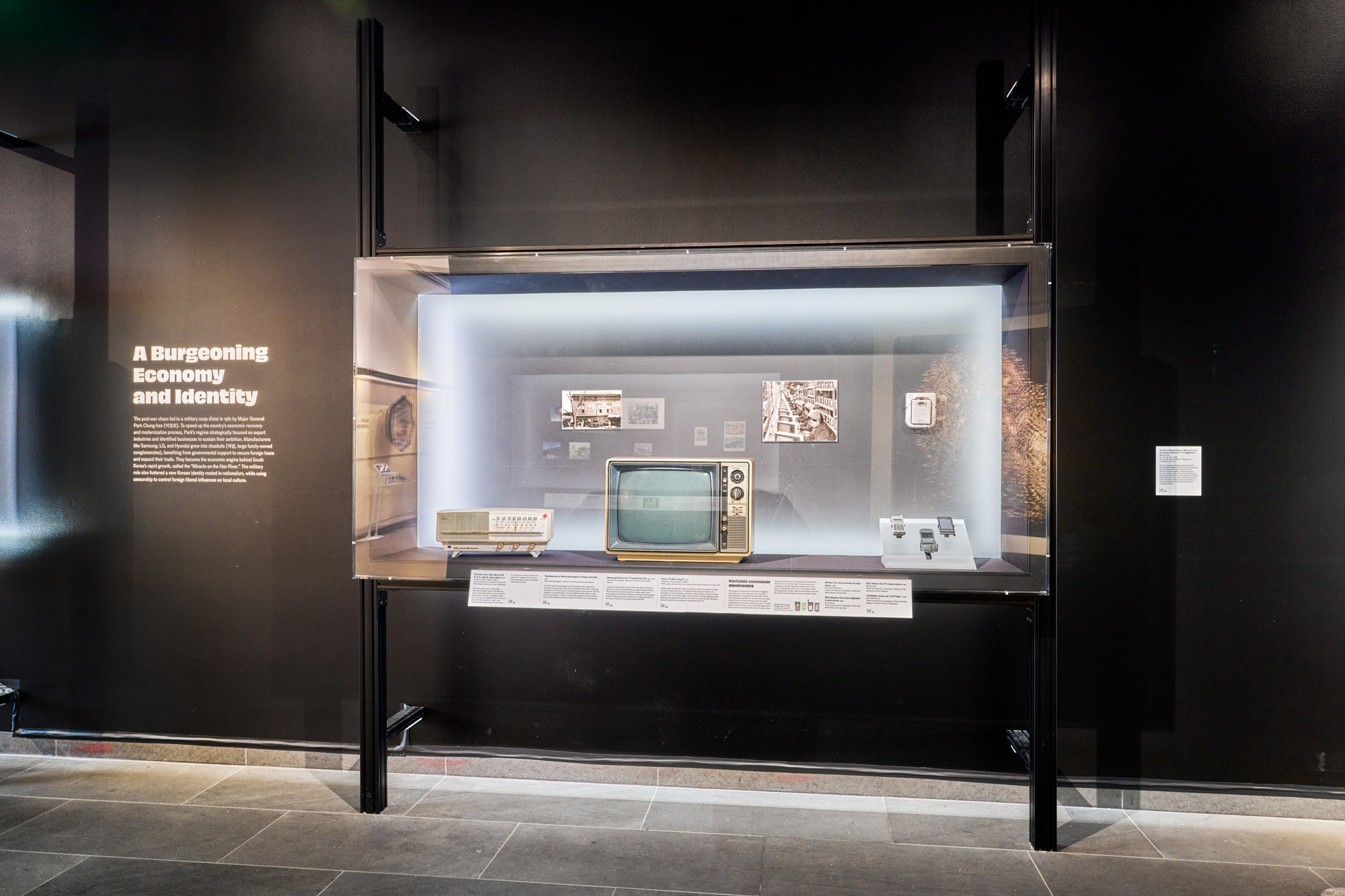 Black walls with glass display case featuring electronics and photographs