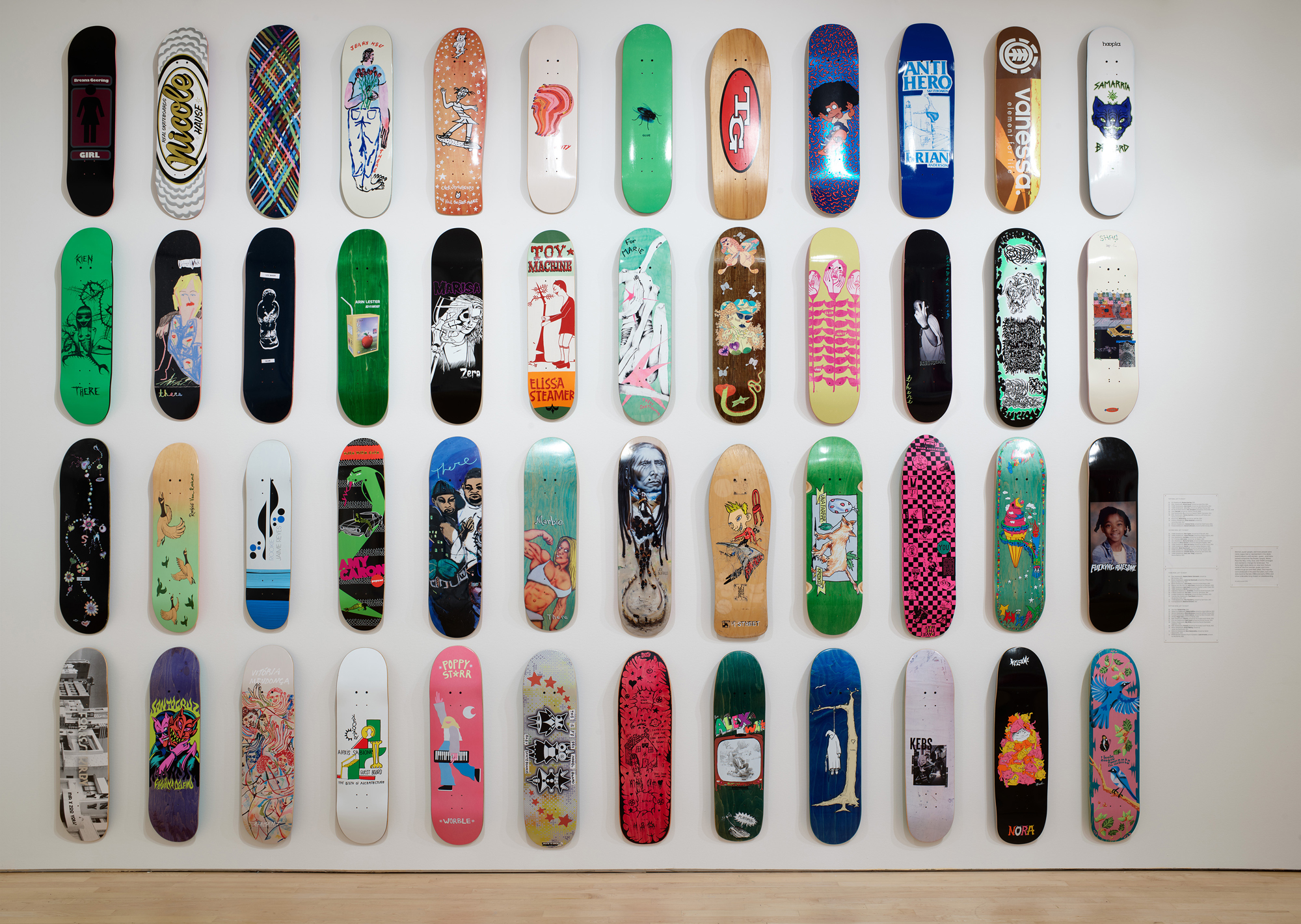 White wall with grid of vertically arranged skate decks