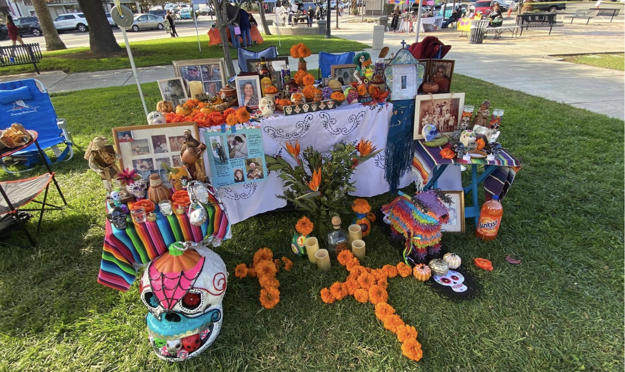 A Day of the Dead altar, decorated with flowers, skulls and crosses, set up on a green lawn. 