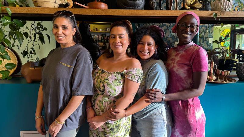 Four female chefs pose for a portrait inside a restaurant.