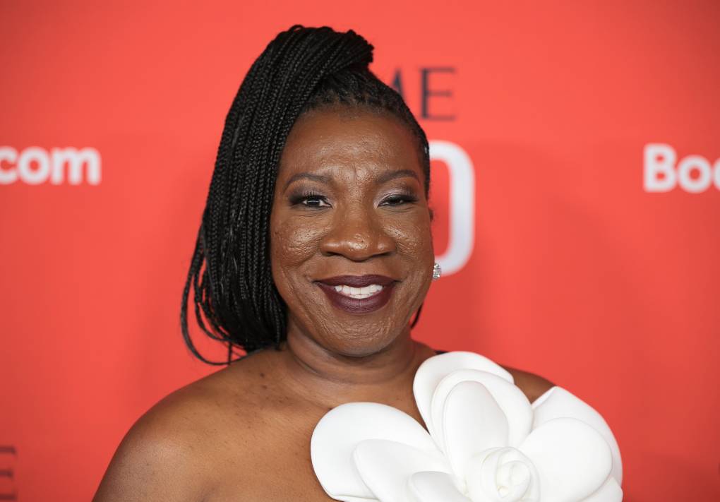 A smiling Black woman with braided hair in a high ponytail, on the red carpet.