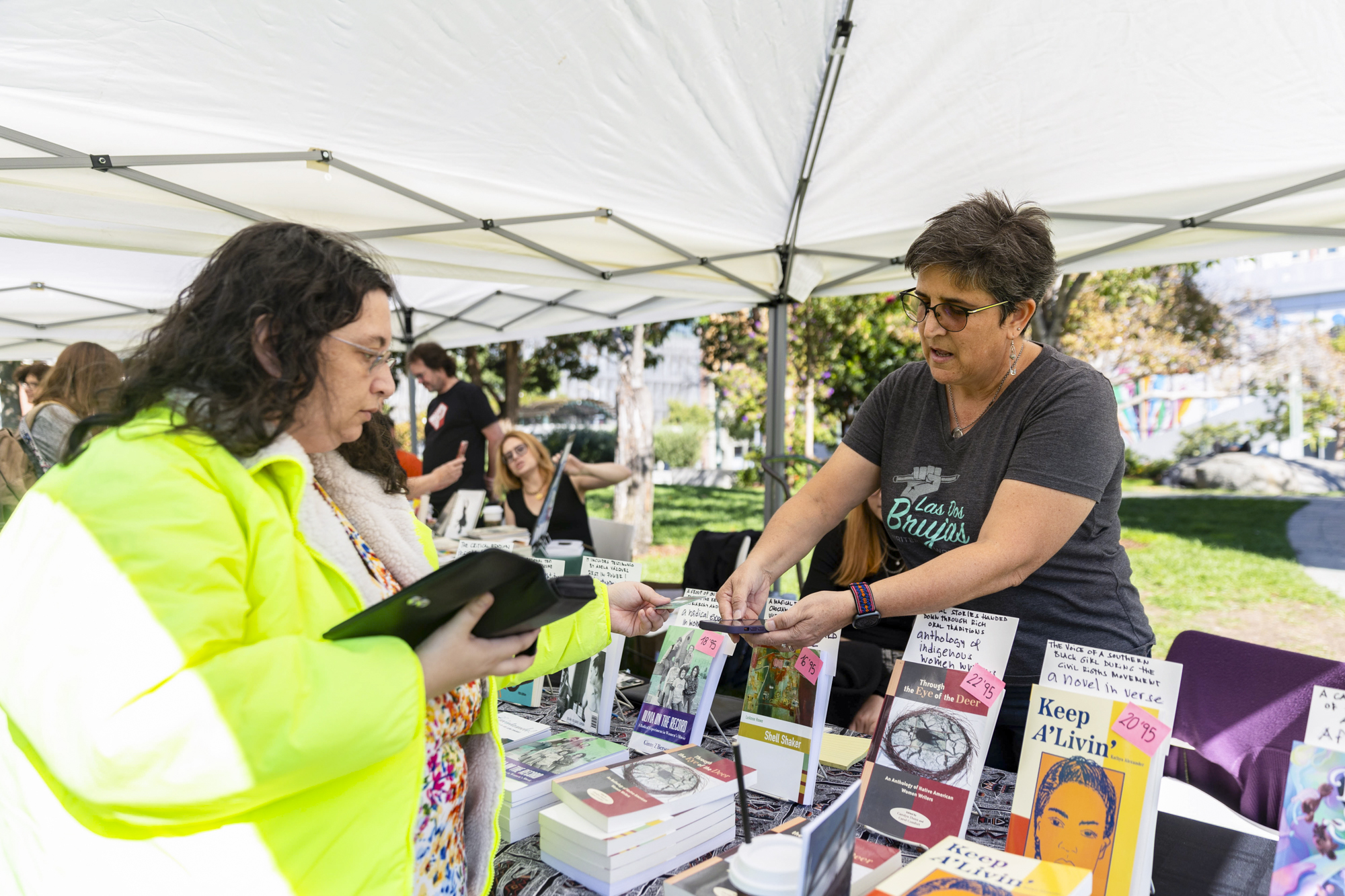 person does a financial transaction on phone over table of books