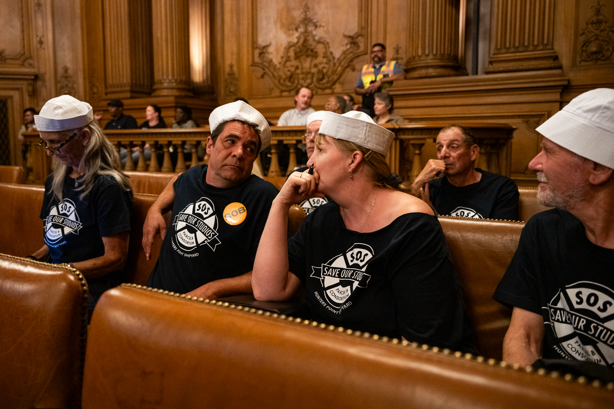 people in matching shirts and sailor hats sit in wooden benches in city building