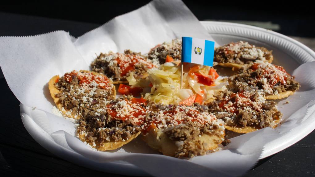 A plate of garnachas (shredded beef topped tortilla chips), decorated with a Guatemalan toothpick flag.