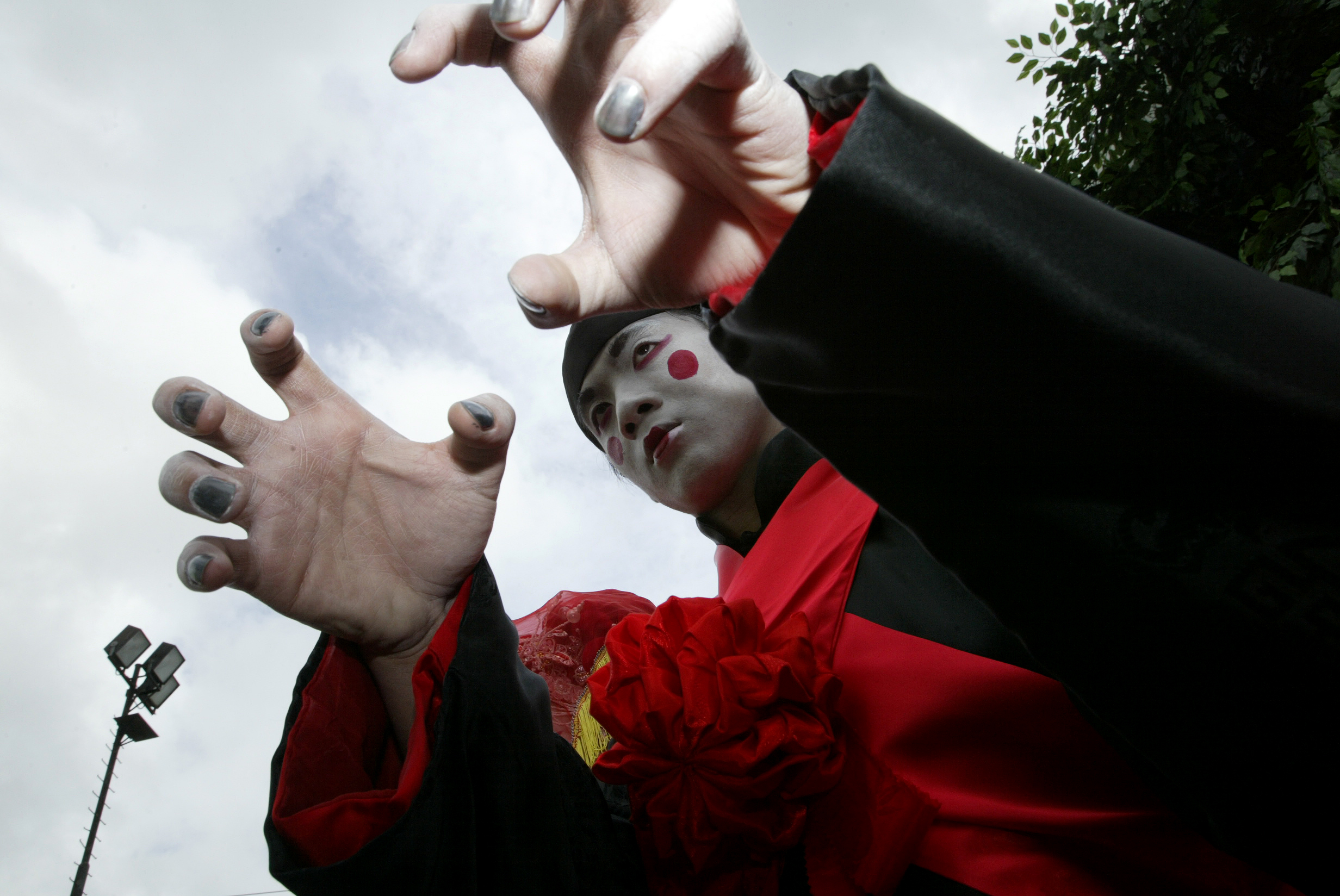 An Asian person in white face paint posing in a menacing position.