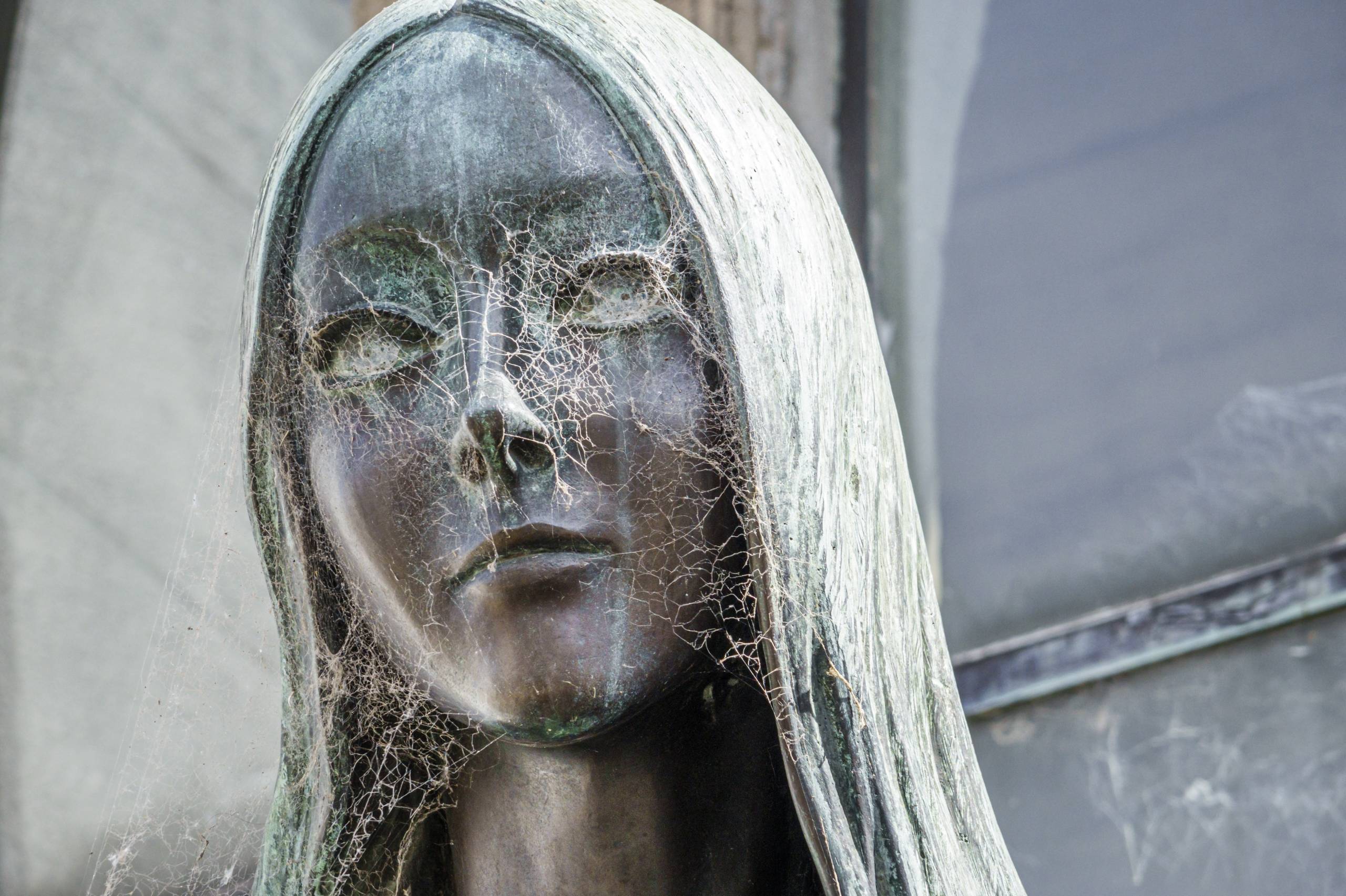 Closeup of a bronze statue of a bride with cobwebs on her face.