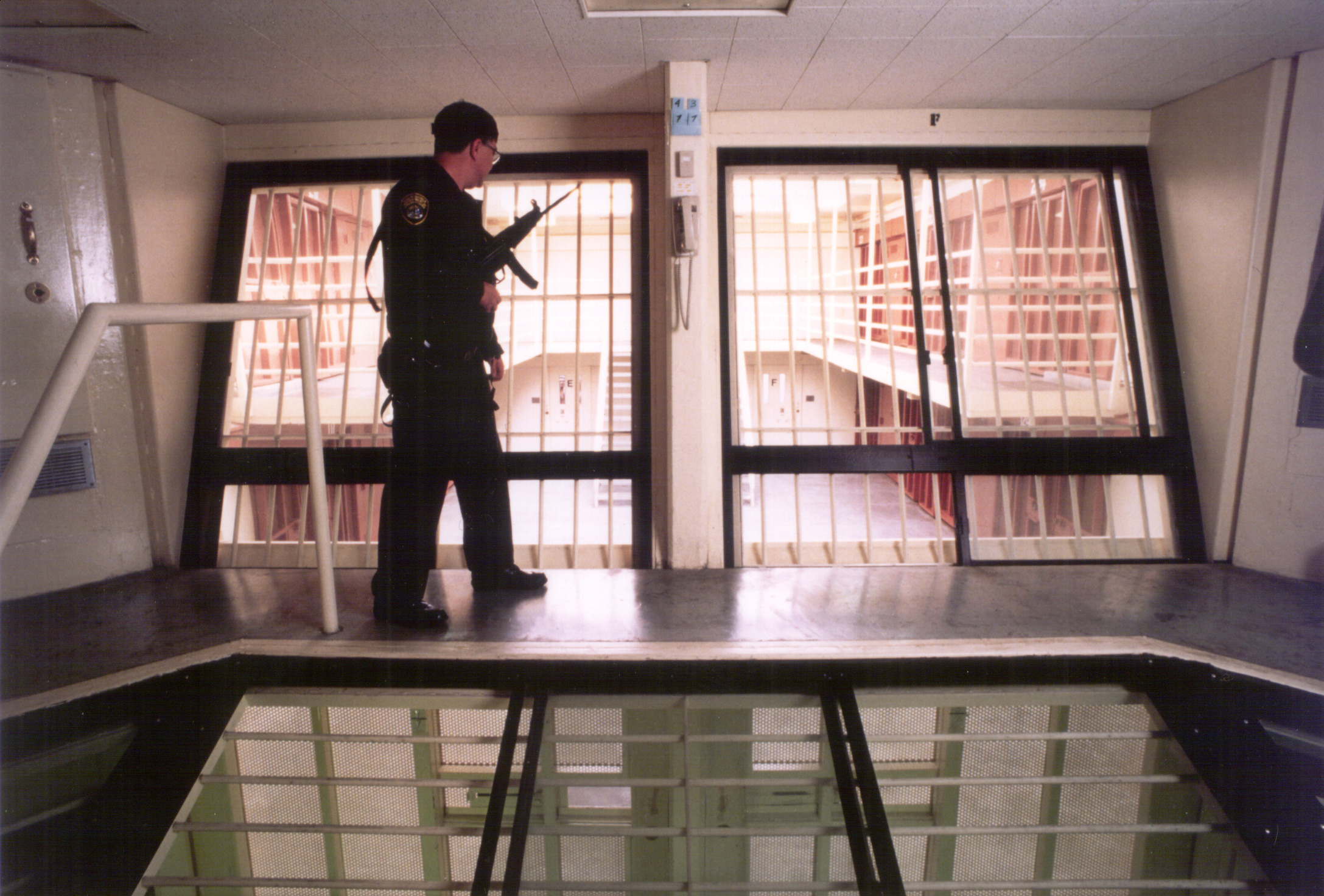 A California prison guard with a gun standing in a watchtower.