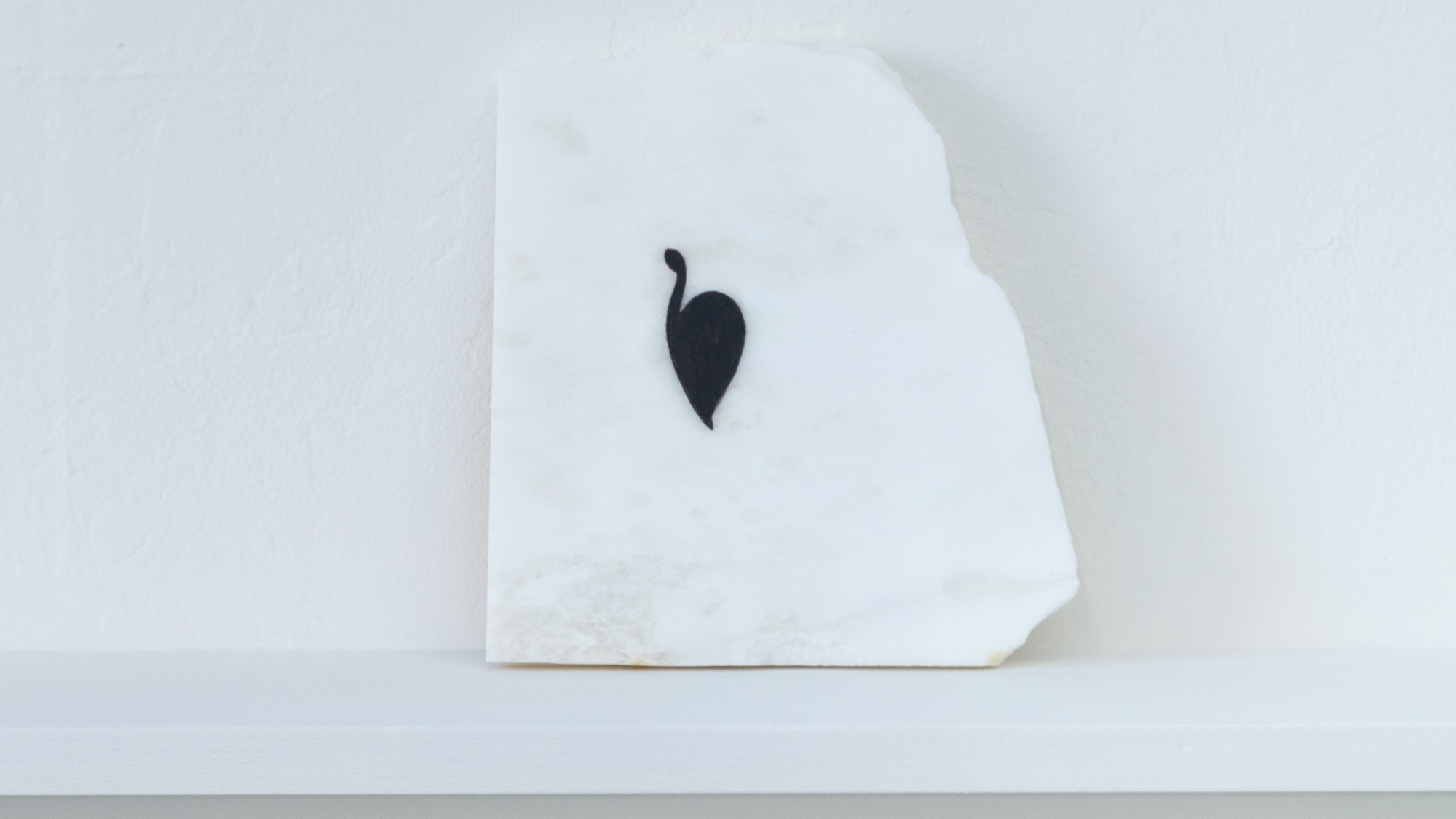 delicate black shape on chunk of white marble on shelf