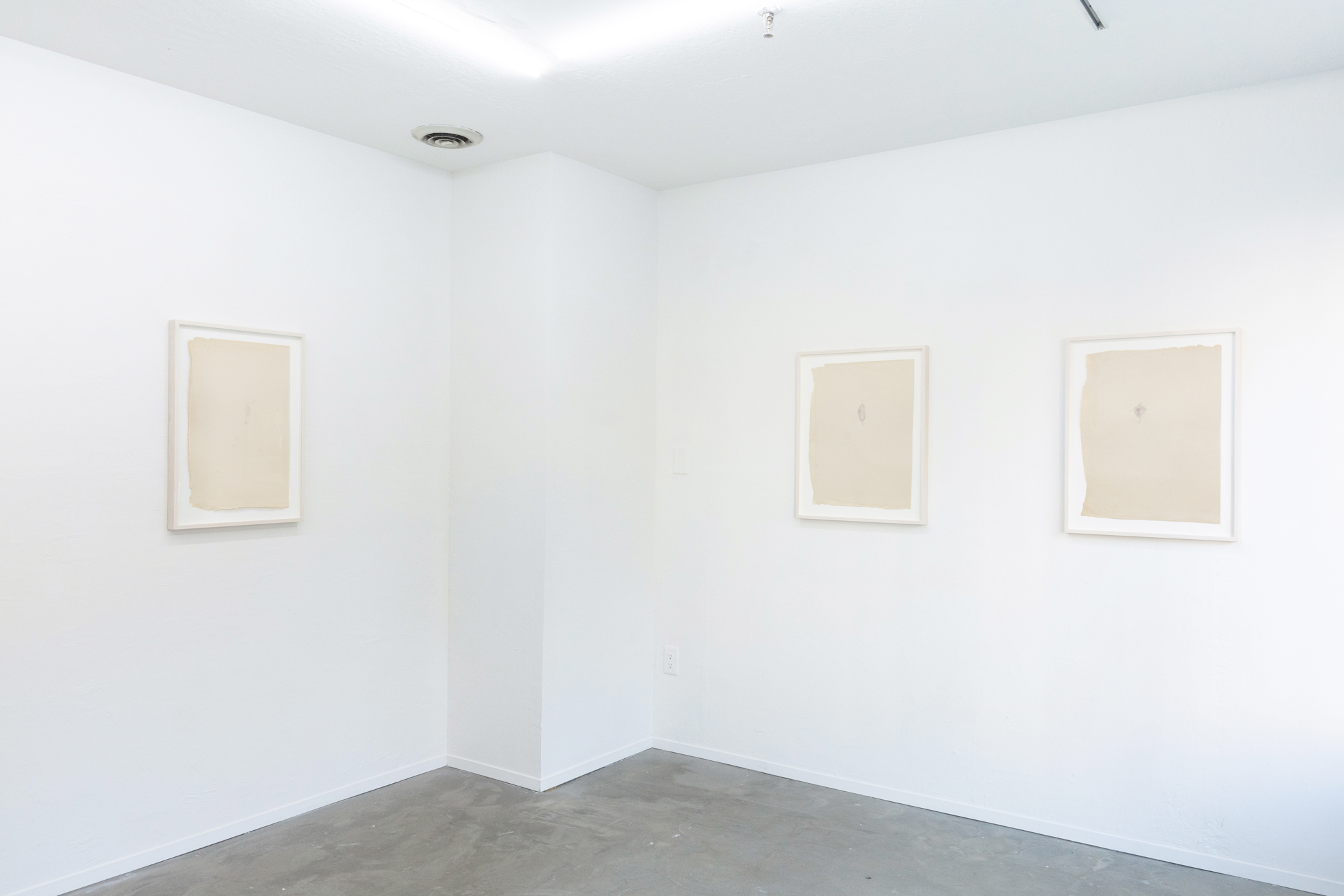 three framed works on paper in white gallery space