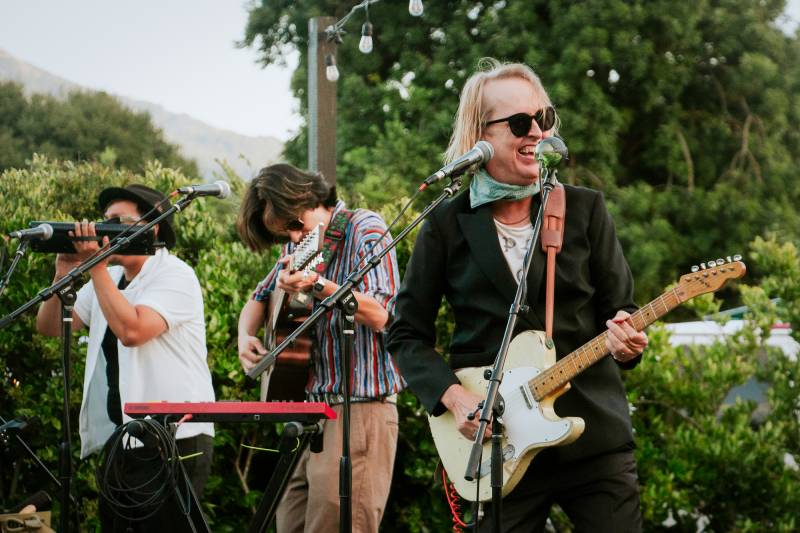 three men play in a band onstage