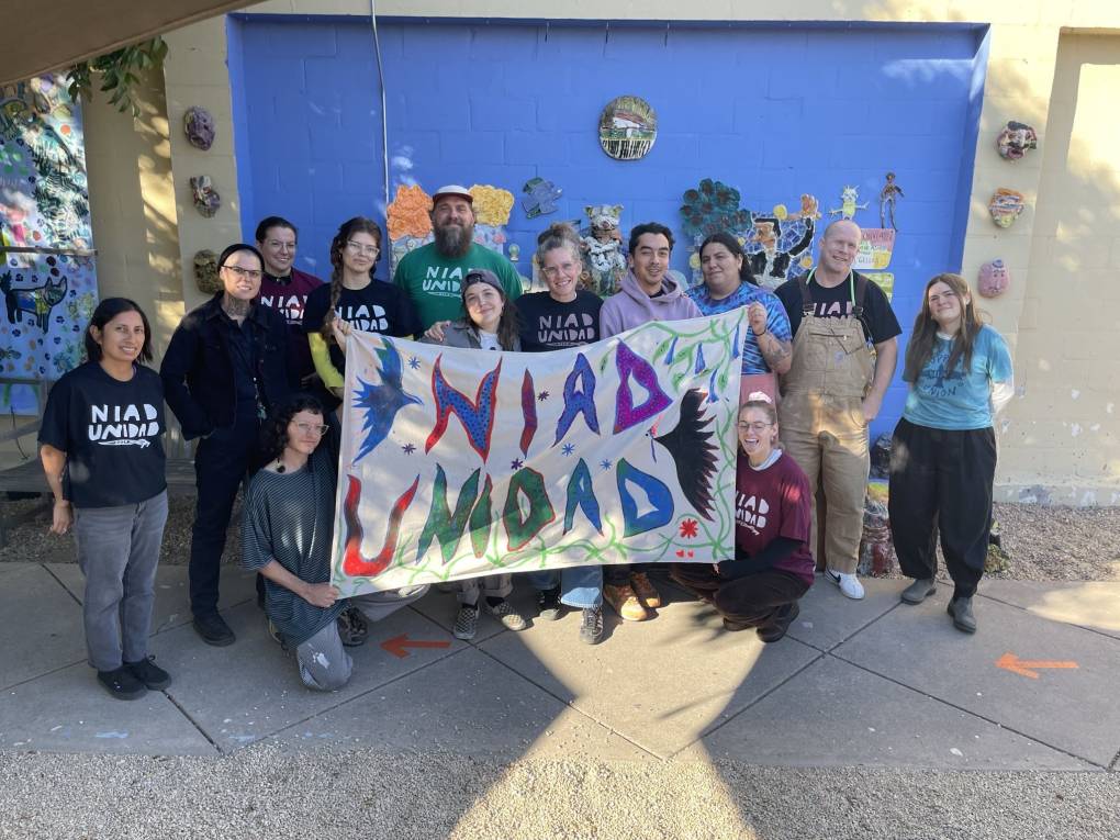 Co-workers hold a union banner that says "NIAD Unidad."