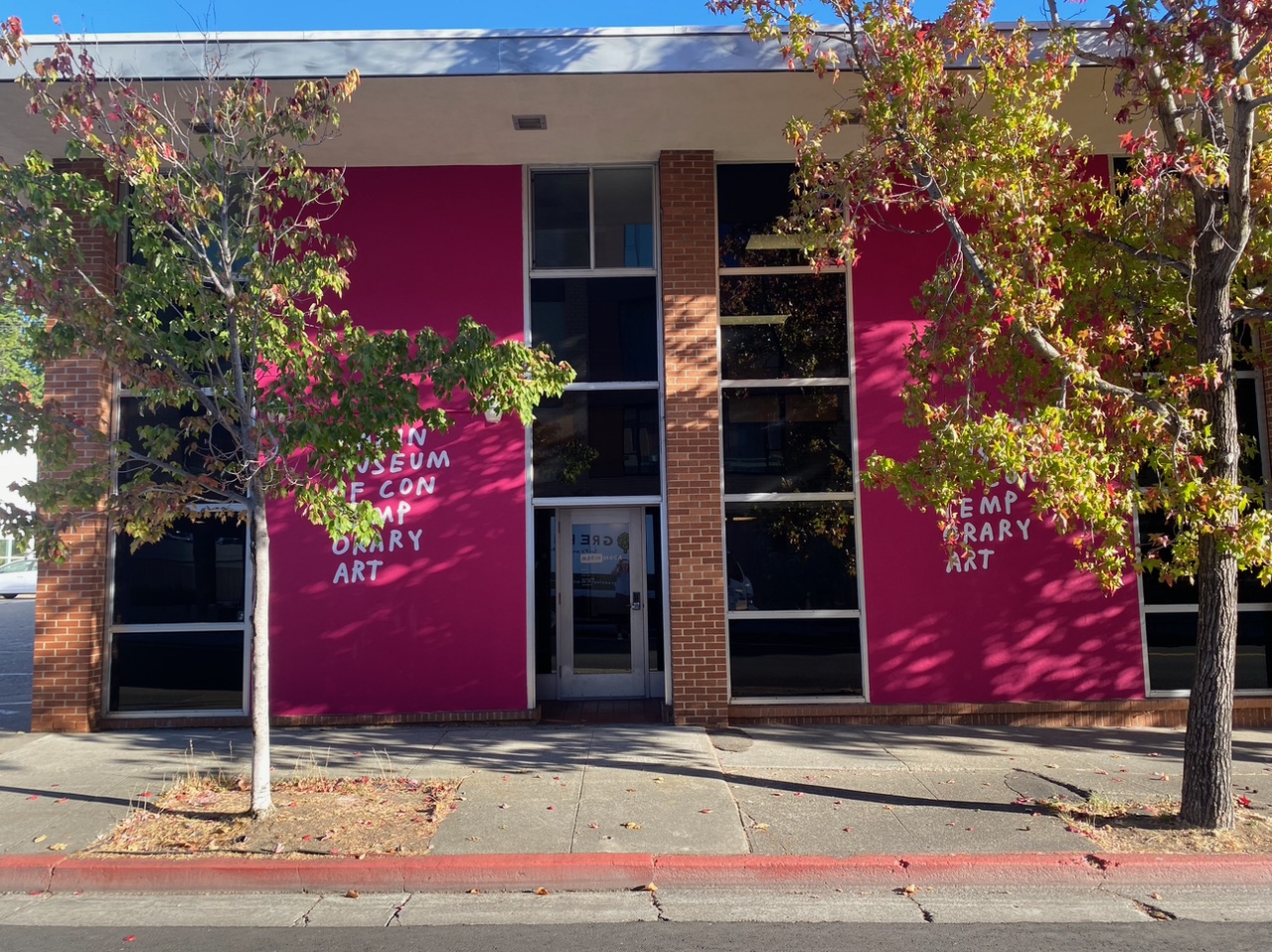 bright pink painted facade of building with trees in sidewalk