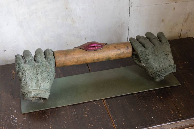 sculpture of two hands holding rolling pin with lips on the wood