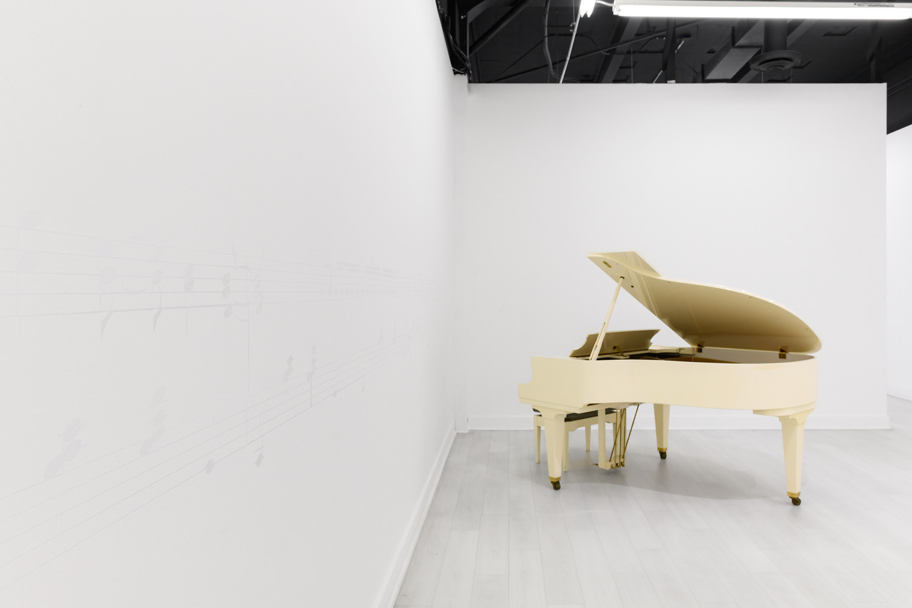 white vinyl musical notes on white wall with ivory grand piano in corner