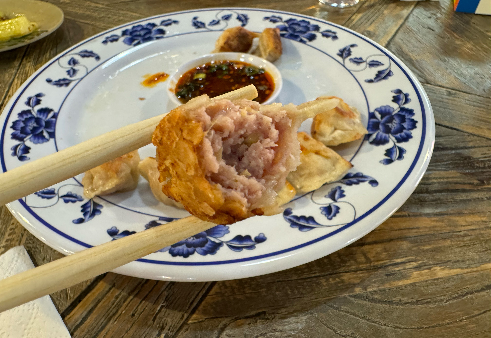 A potsticker, bitten so that its meaty filling is visible.