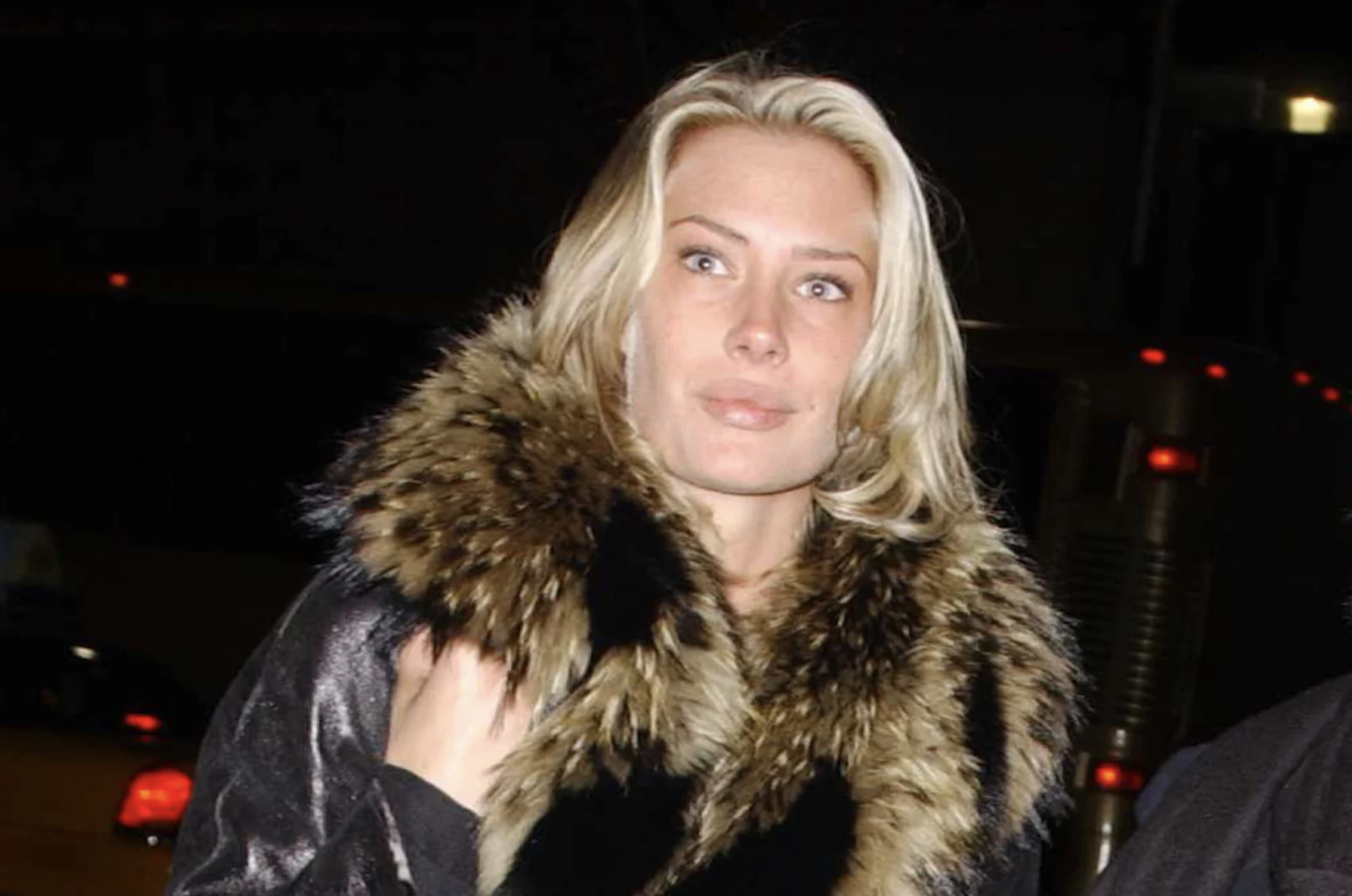 A beautiful blond woman wearing a coat with a fur collar.