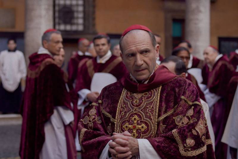 A group of holy men in formal robes gather in a courtyard.