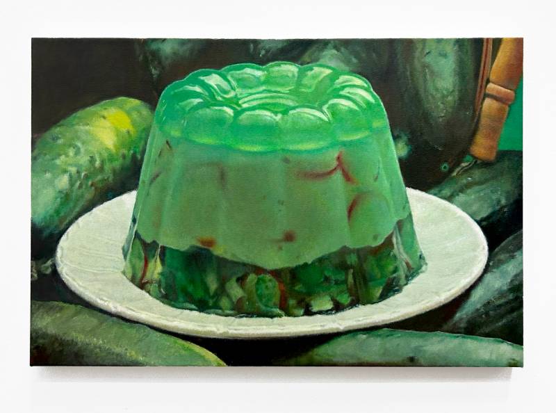 painting of green Jello dish with vegetables inside and cucumbers around plate