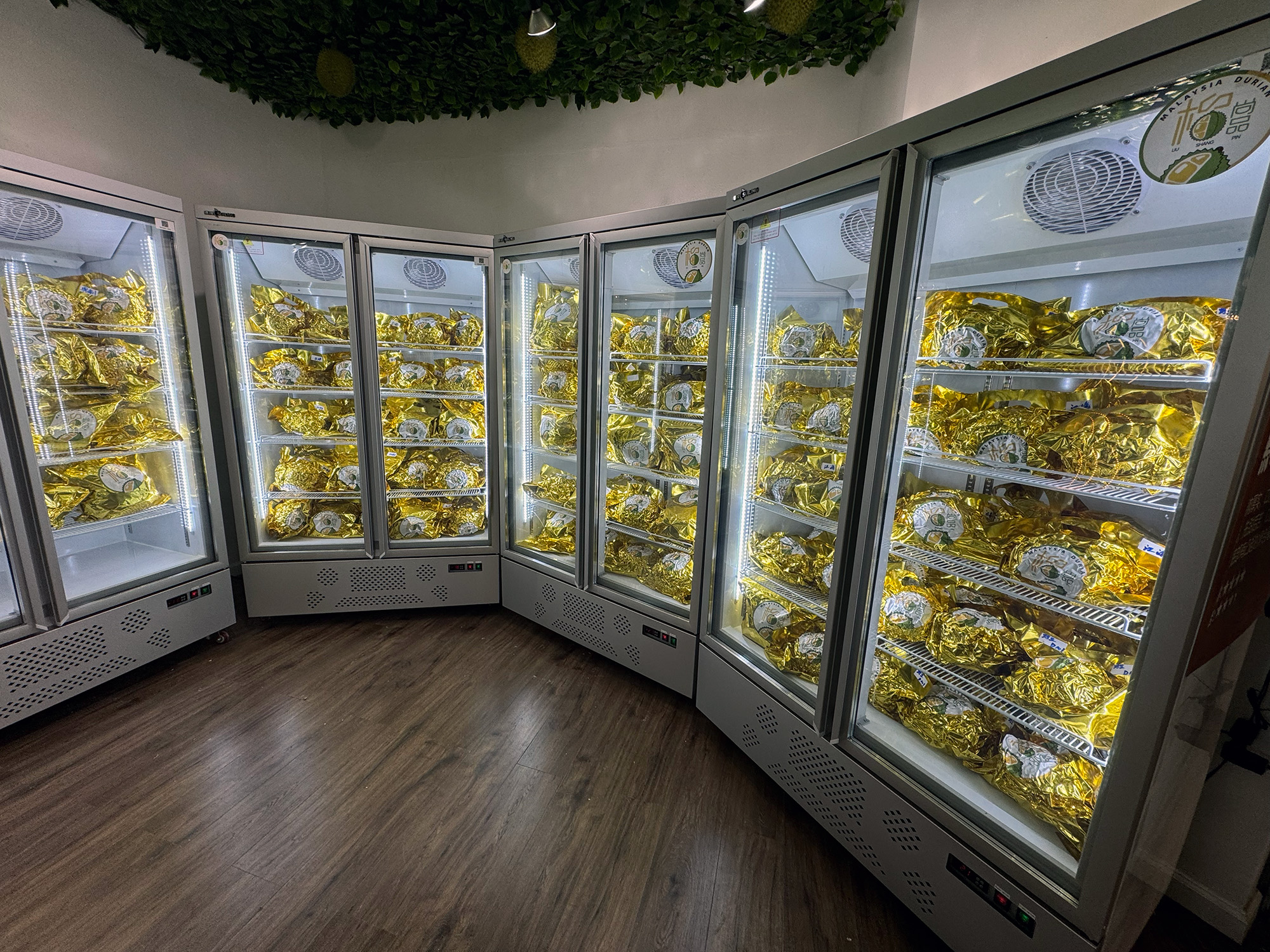 Freezer cases filled with dozens of gold foil wrapped durians.