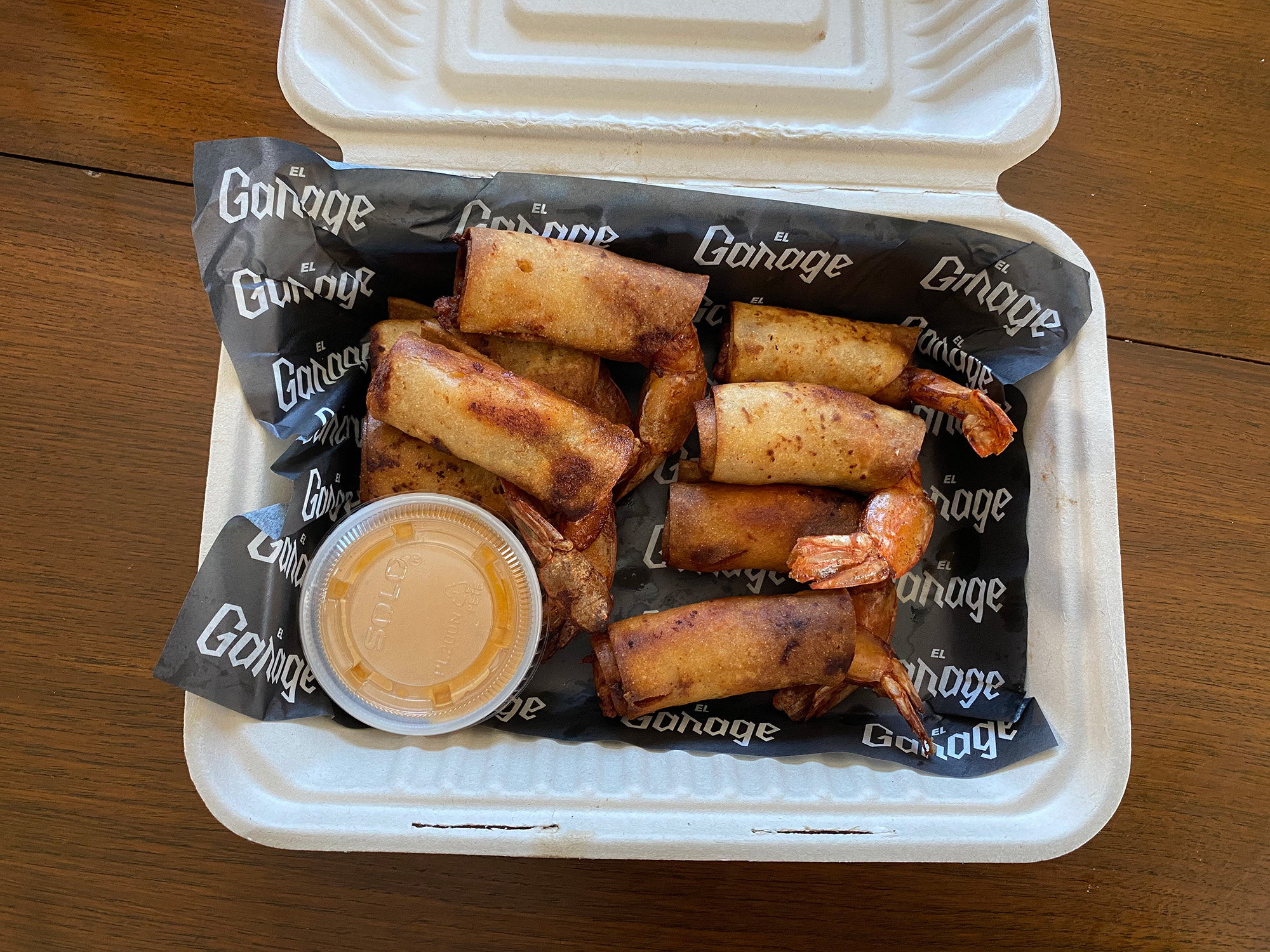 Shrimp taquitos in a takeout container.