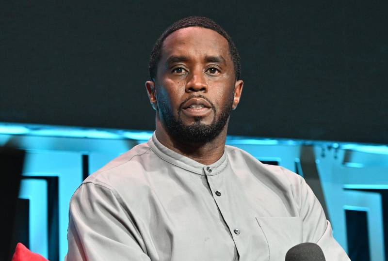 A Black man sits on a stage looking confused.