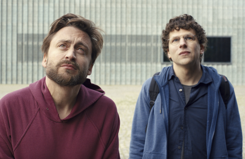 Two scruffy white men stand looking somberly upwards.