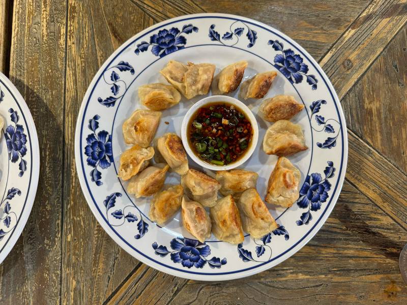 Overhead view of a plate of potstickers, with a chili-infused dipping sauce.