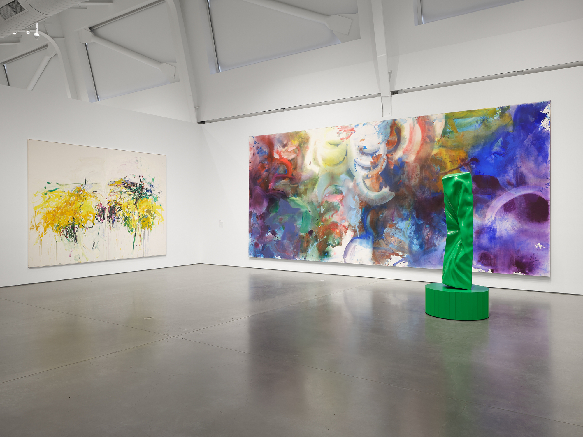 two giant colorful abstract expressionist paintings and a bright green punched monolith sculpture