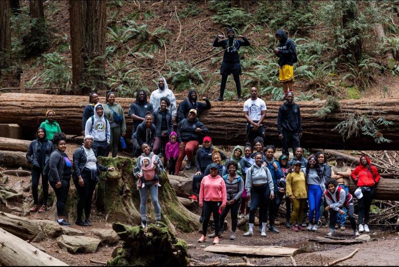 Hikers pose for a photo on some fallen redwood trees.